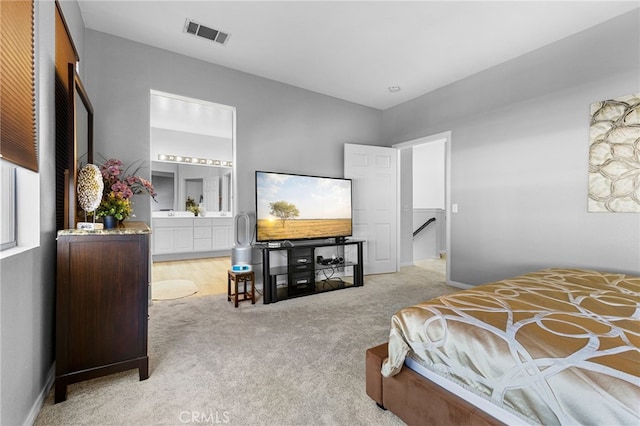 bedroom featuring ensuite bath and light colored carpet