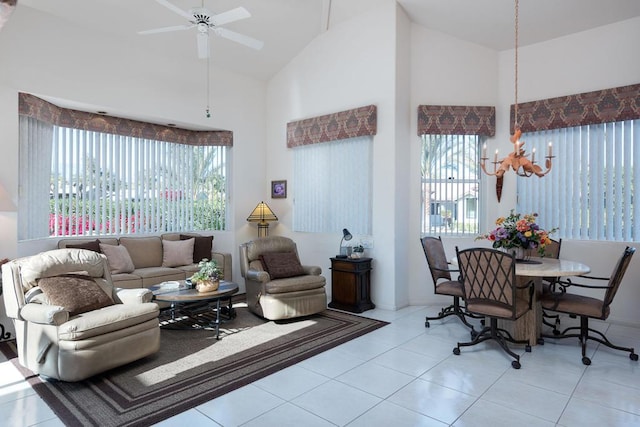 living room featuring light tile patterned floors, ceiling fan with notable chandelier, and high vaulted ceiling