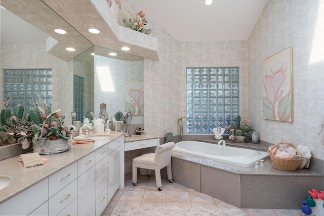 bathroom with a relaxing tiled tub, tile walls, vanity, and tile patterned flooring