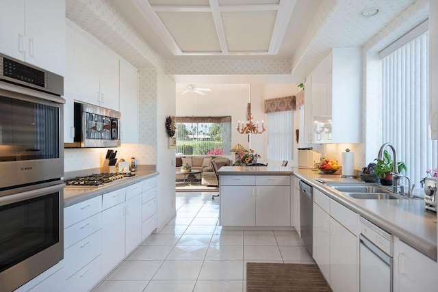 kitchen featuring kitchen peninsula, sink, light tile patterned flooring, white cabinetry, and appliances with stainless steel finishes