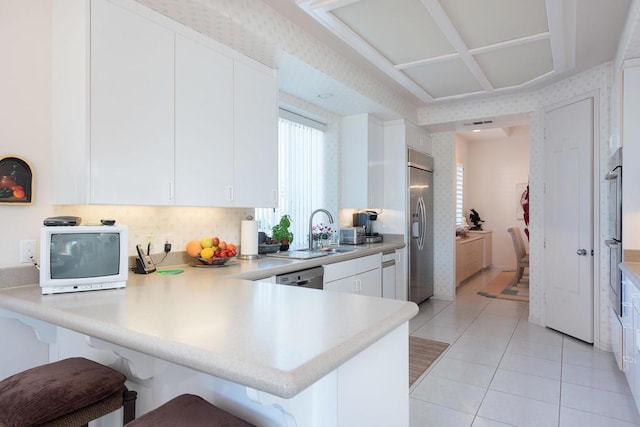 kitchen featuring kitchen peninsula, sink, white cabinetry, stainless steel appliances, and light tile patterned floors