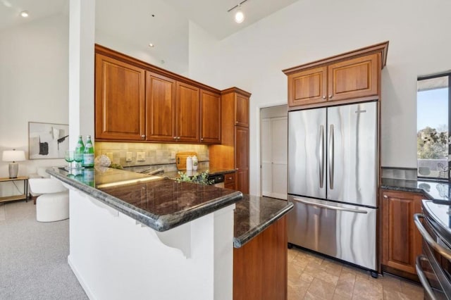 kitchen featuring dark stone countertops, kitchen peninsula, decorative backsplash, a breakfast bar area, and stainless steel appliances