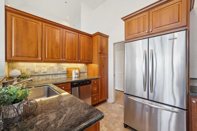 kitchen with stainless steel appliances, decorative backsplash, a high ceiling, dark stone counters, and sink