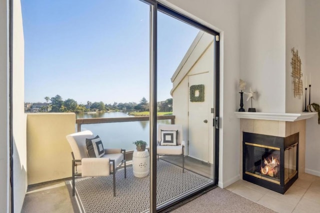 doorway to outside featuring light tile patterned floors, a water view, and a fireplace