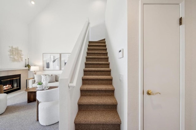 stairs with a fireplace and carpet flooring