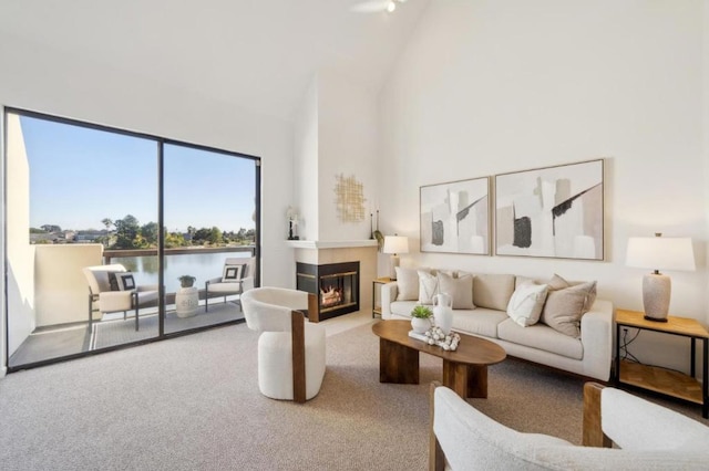 carpeted living room with a water view and a towering ceiling