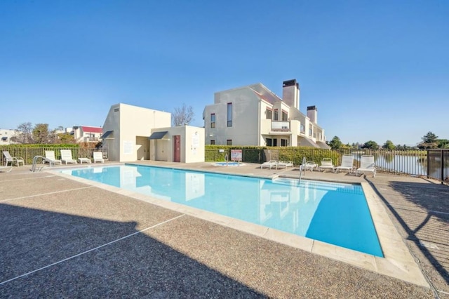 view of pool featuring a water view and a patio area