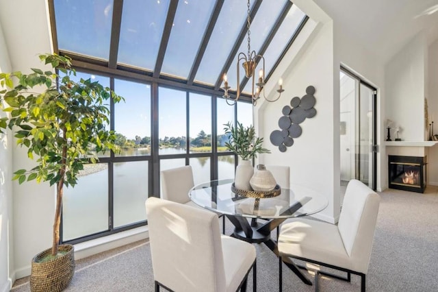 dining room featuring carpet, a towering ceiling, an inviting chandelier, a water view, and floor to ceiling windows