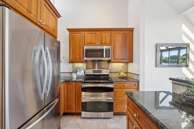 kitchen featuring backsplash, appliances with stainless steel finishes, and dark stone countertops