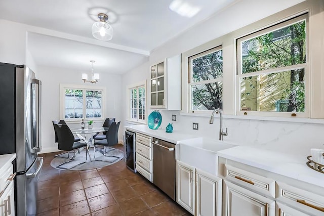 kitchen featuring pendant lighting, sink, white cabinets, a chandelier, and stainless steel appliances