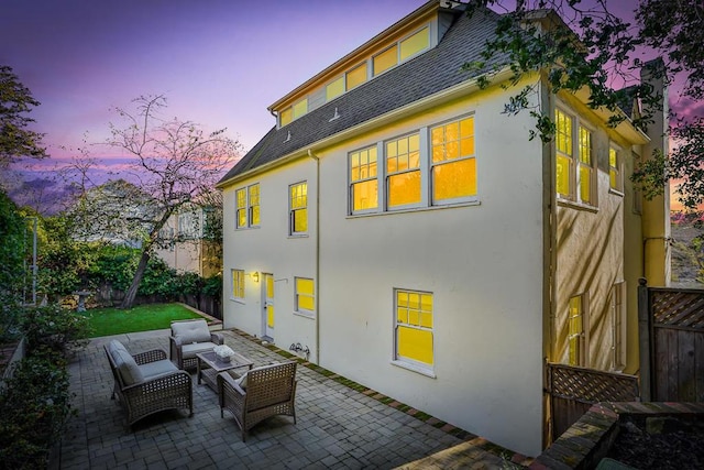 back house at dusk featuring a patio area and an outdoor hangout area