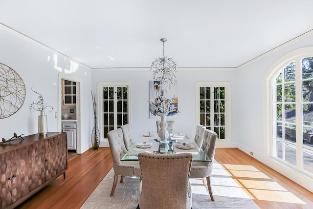 dining room with light hardwood / wood-style flooring, ornamental molding, and a chandelier