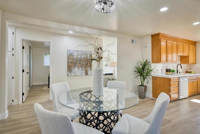 dining space with sink, a chandelier, and light hardwood / wood-style floors