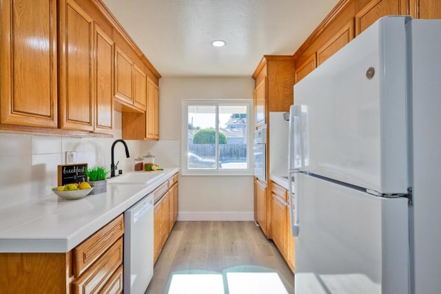 kitchen with sink, white appliances, and light hardwood / wood-style floors