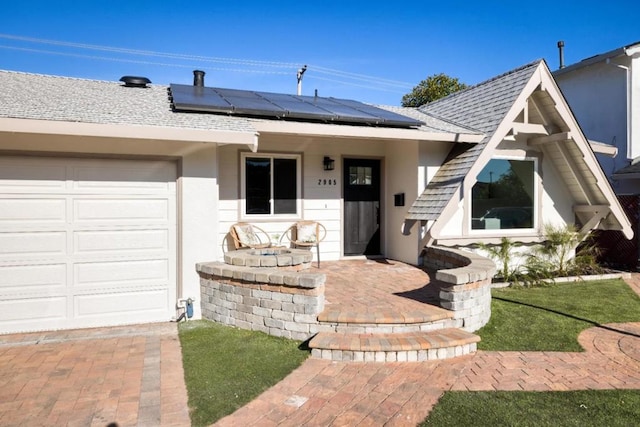 ranch-style house featuring a garage and solar panels