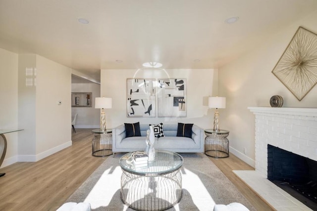 living room with a brick fireplace and light hardwood / wood-style floors