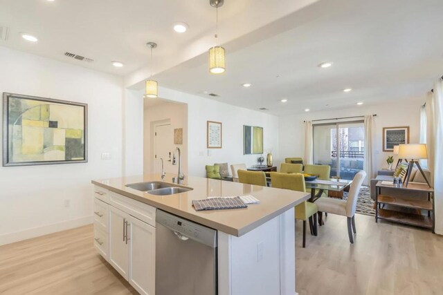 kitchen with dishwasher, sink, white cabinets, hanging light fixtures, and a kitchen island with sink