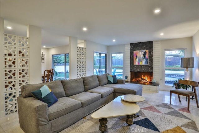 living room featuring a brick fireplace and light tile patterned floors