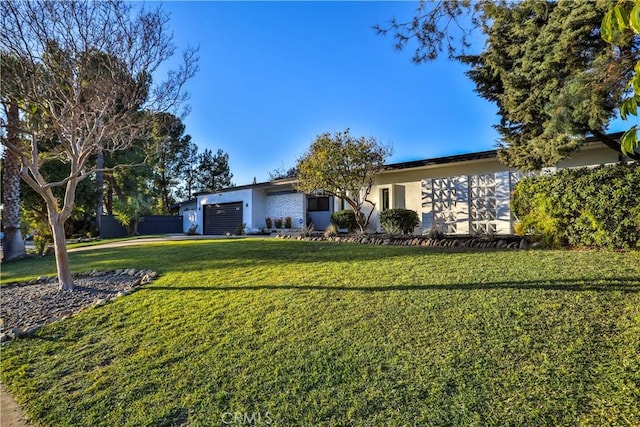 ranch-style house featuring a front lawn and a garage