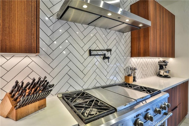 kitchen with backsplash, high end range, and wall chimney exhaust hood