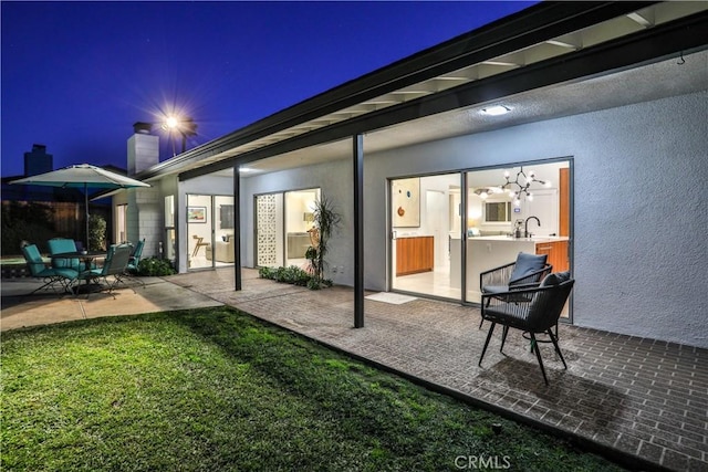 back house at twilight with sink and a patio