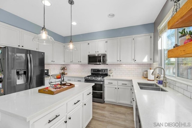 kitchen featuring white cabinets, stainless steel appliances, sink, backsplash, and light hardwood / wood-style flooring