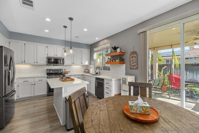 kitchen with a center island, hanging light fixtures, black appliances, white cabinets, and sink