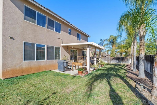 rear view of house with ceiling fan, a patio area, and a lawn