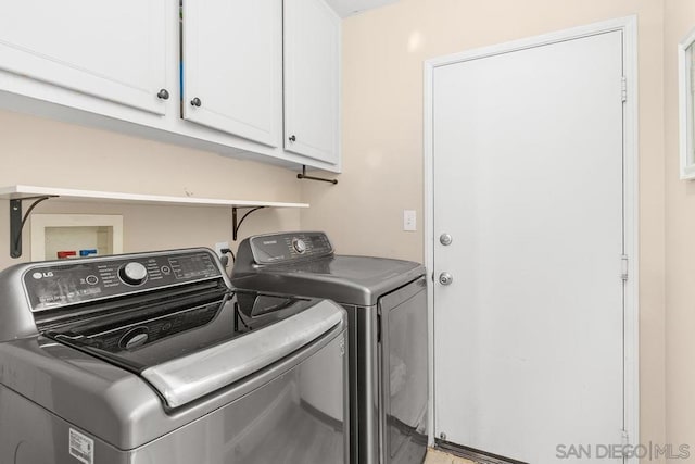 washroom featuring cabinets and washer and clothes dryer