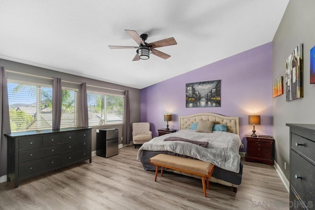 bedroom with vaulted ceiling, ceiling fan, refrigerator, and light wood-type flooring