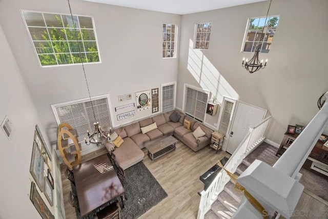 living room with an inviting chandelier, a towering ceiling, and wood-type flooring