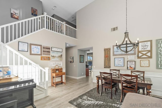 dining space with a towering ceiling, an inviting chandelier, and light hardwood / wood-style flooring