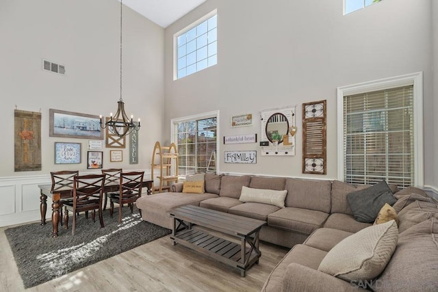 living room featuring a towering ceiling, a chandelier, and hardwood / wood-style floors