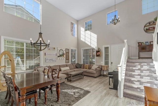 living room featuring a chandelier, a towering ceiling, and light hardwood / wood-style flooring