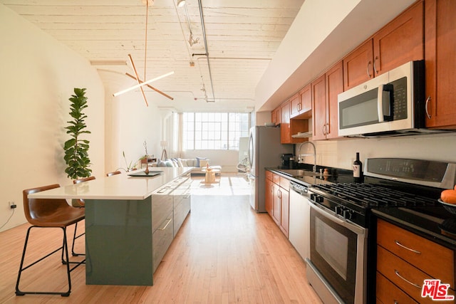 kitchen with a breakfast bar area, stainless steel appliances, track lighting, and wooden ceiling