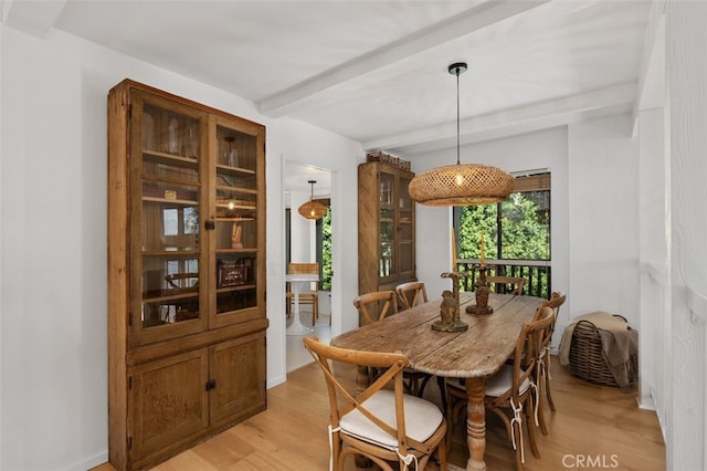 dining area featuring light wood-type flooring and beamed ceiling