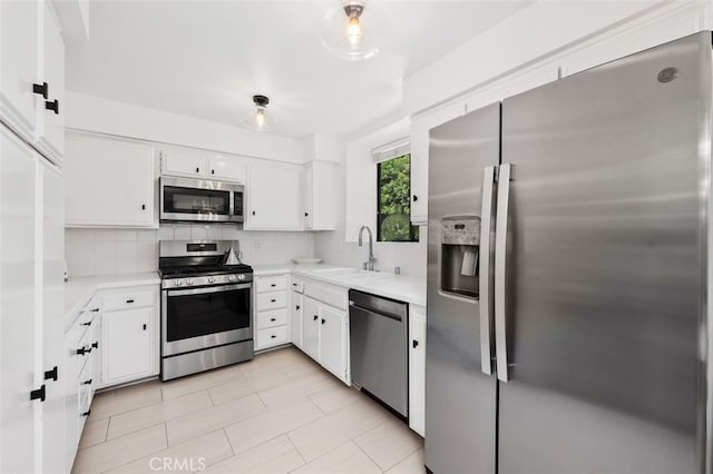 kitchen with white cabinetry, stainless steel appliances, decorative backsplash, sink, and light tile patterned flooring