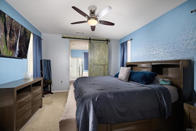 bedroom with ceiling fan, a barn door, and light colored carpet