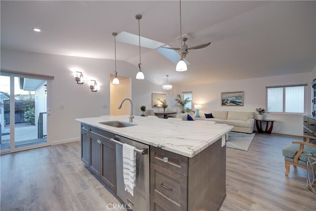 kitchen featuring ceiling fan, dishwasher, sink, hanging light fixtures, and light stone counters