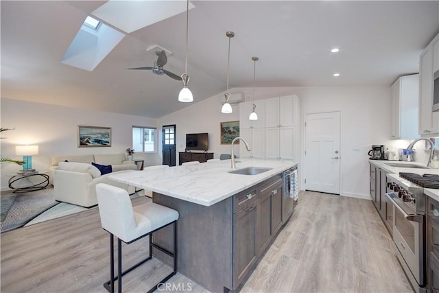 kitchen featuring appliances with stainless steel finishes, white cabinetry, decorative light fixtures, and sink