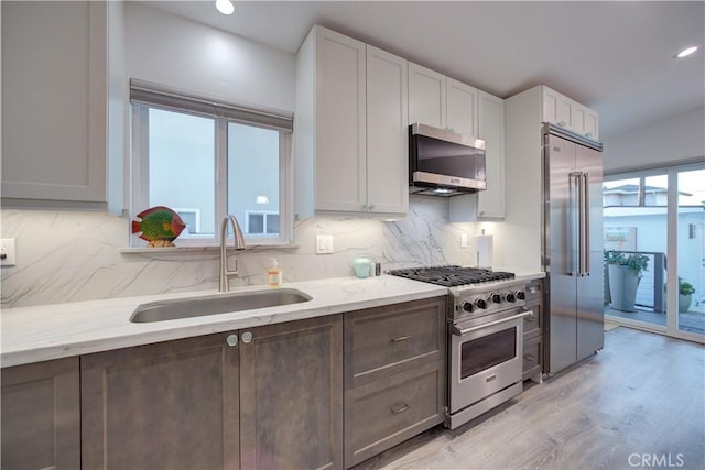 29 11th St, Cayucos, CA 93430 - kitchen featuring high end appliances, decorative backsplash, light stone countertops, light wood finished floors, and recessed lighting