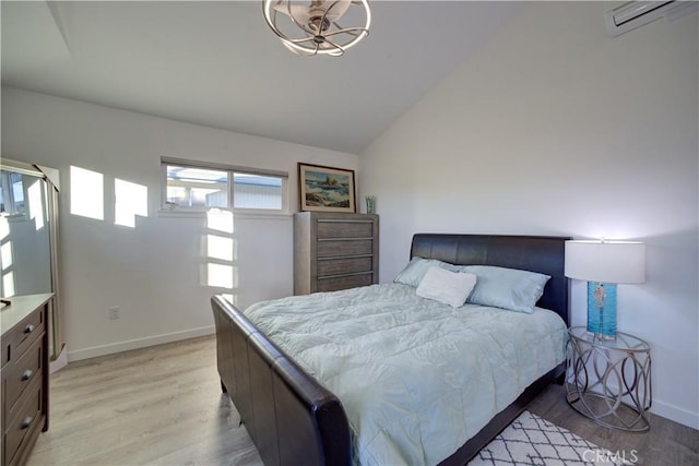 bedroom with vaulted ceiling, a wall mounted air conditioner, and light hardwood / wood-style floors