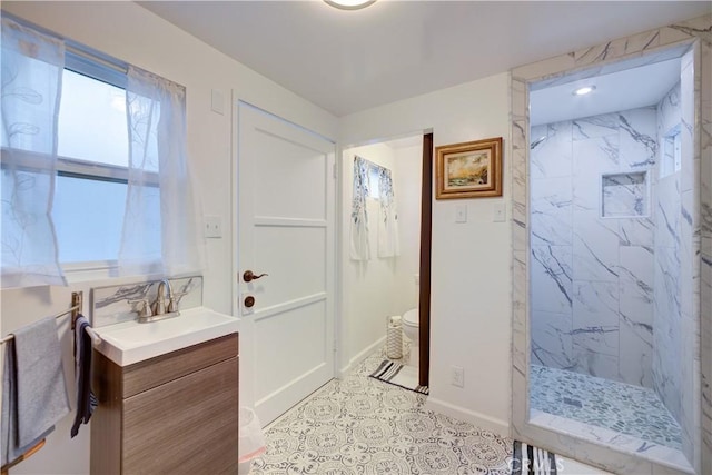 bathroom featuring toilet, tiled shower, and vanity