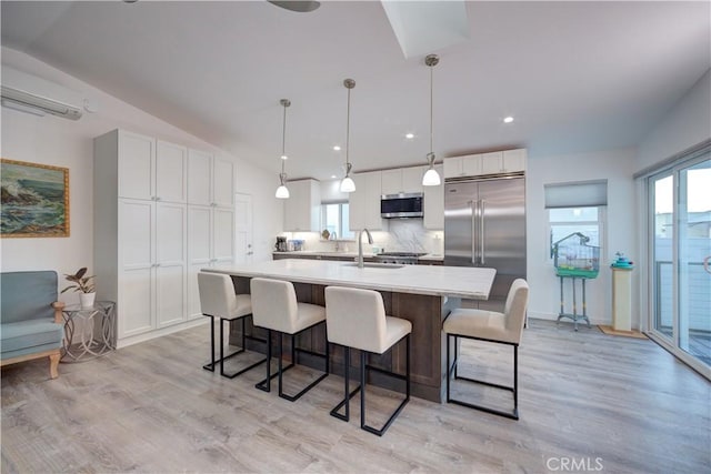 kitchen with hanging light fixtures, appliances with stainless steel finishes, white cabinetry, and lofted ceiling