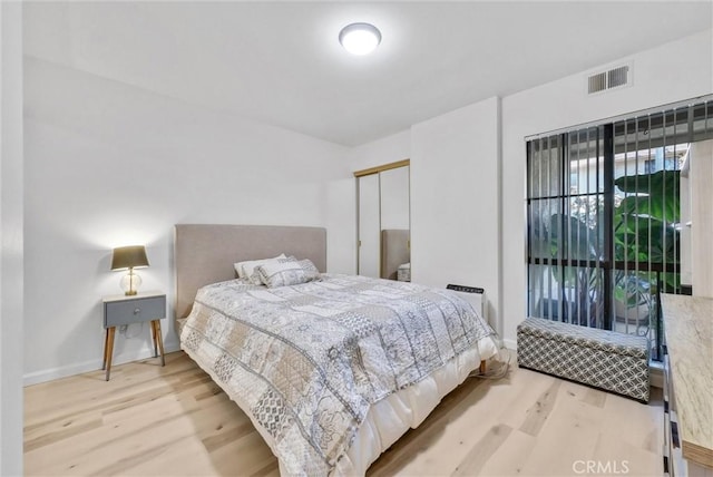 bedroom with light hardwood / wood-style floors and a closet