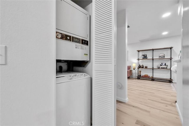 laundry room featuring light hardwood / wood-style floors and stacked washer / dryer