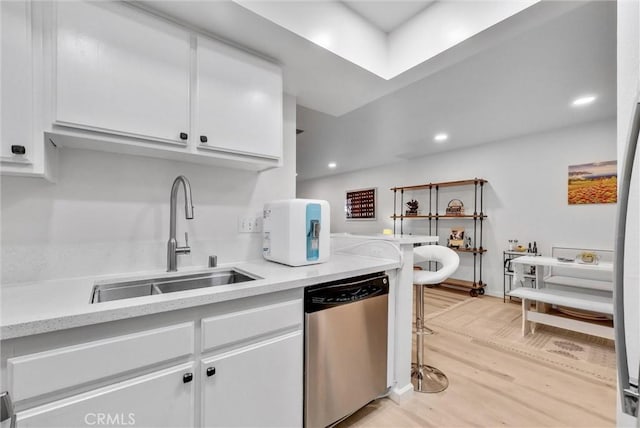 kitchen featuring dishwasher, sink, white cabinetry, and light hardwood / wood-style floors