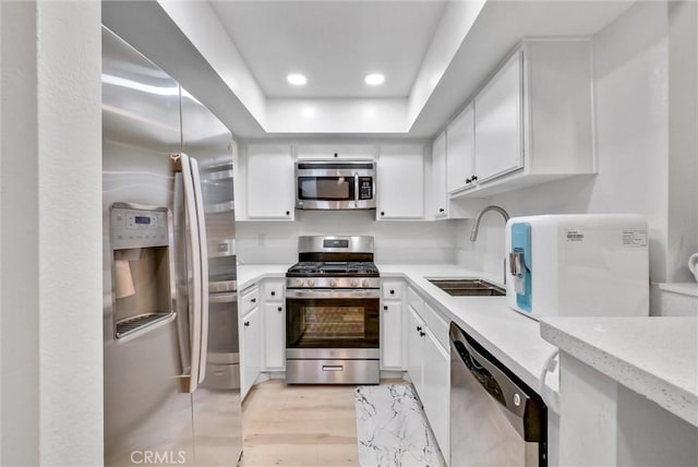 kitchen with white cabinets, sink, light stone counters, and stainless steel appliances