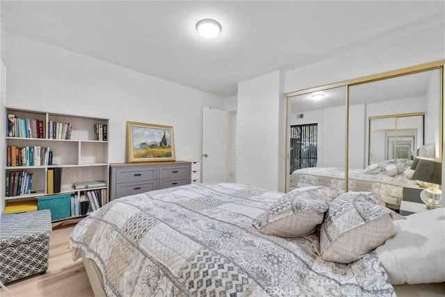 bedroom with light hardwood / wood-style floors and a closet