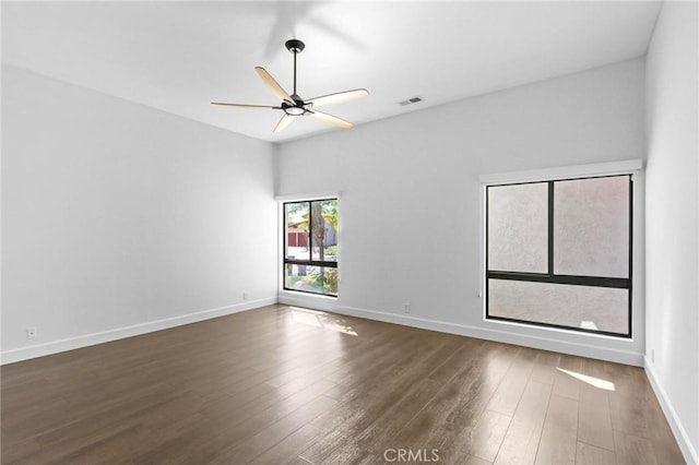 empty room featuring a ceiling fan, visible vents, baseboards, and wood finished floors